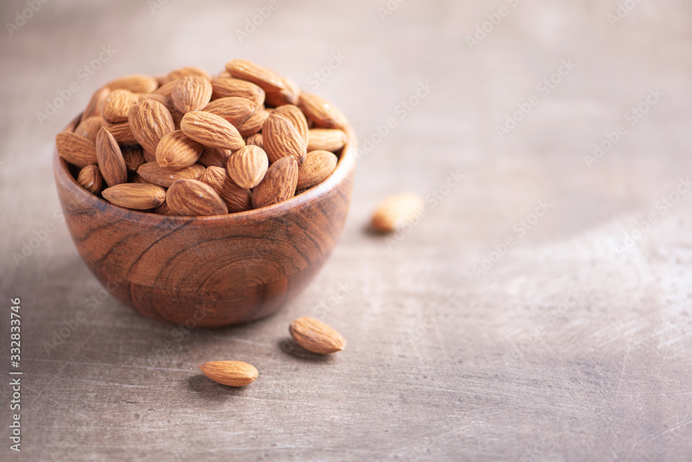 Almond nuts in wooden bowl on wood textured background. Copy space. Superfood, vegan, vegetarian food concept. Macro of almond nut texture, selective focus. Healthy snack Almond nuts in wooden bowl on wood textured background. Copy space. Superfood, vegan, vegetarian food concept. Macro of almond nut texture, selective focus. Healthy snack