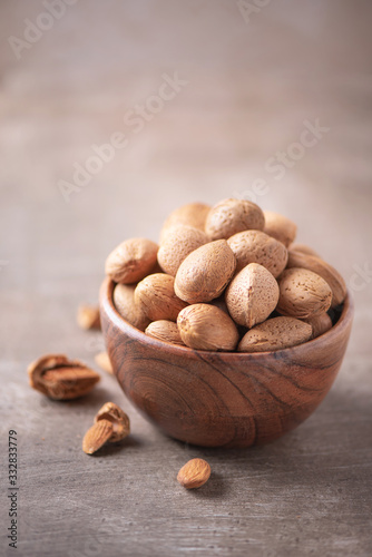 Almond nuts in wooden bowl on wood textured background. Copy space. Superfood, vegan, vegetarian food concept. Macro of almond nut texture, selective focus. Healthy snack photo