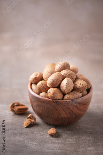 Almond nuts in wooden bowl on wood textured background. Copy space. Superfood, vegan, vegetarian food concept. Macro of almond nut texture, selective focus. Healthy snack