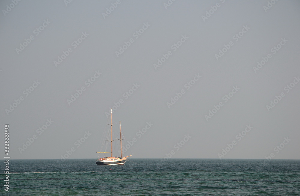 double mast old wooden yacht in the sea on grey sky background double mast old wooden yacht in the sea on grey sky background