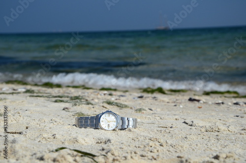 wrist mechanical watch lying on the sand at the ocean beach