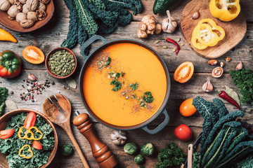 Vegan diet. Autumn harvest. Healthy, clean food and eating concept. Zero waste. Pumpkin soup with vegetarian cooking ingredients, wooden spoons, kitchen utensils on wooden background. Top view