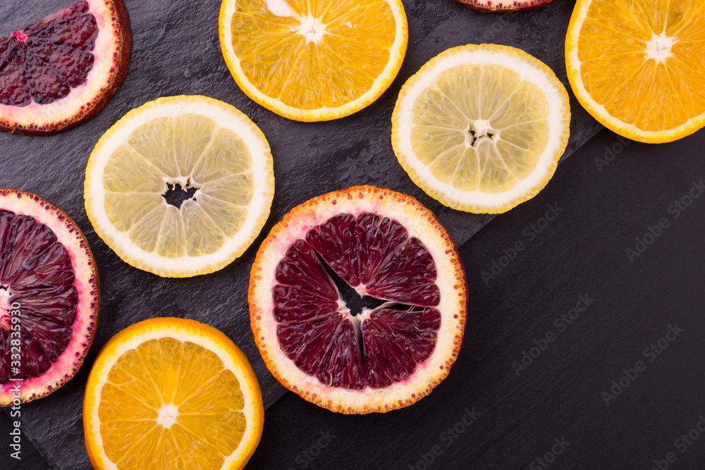 Fresh ripe citruses. Lemons, red oranges and oranges on dark stone background. Copy space Fresh ripe citruses. Lemons, red oranges and oranges on dark stone background. Copy space