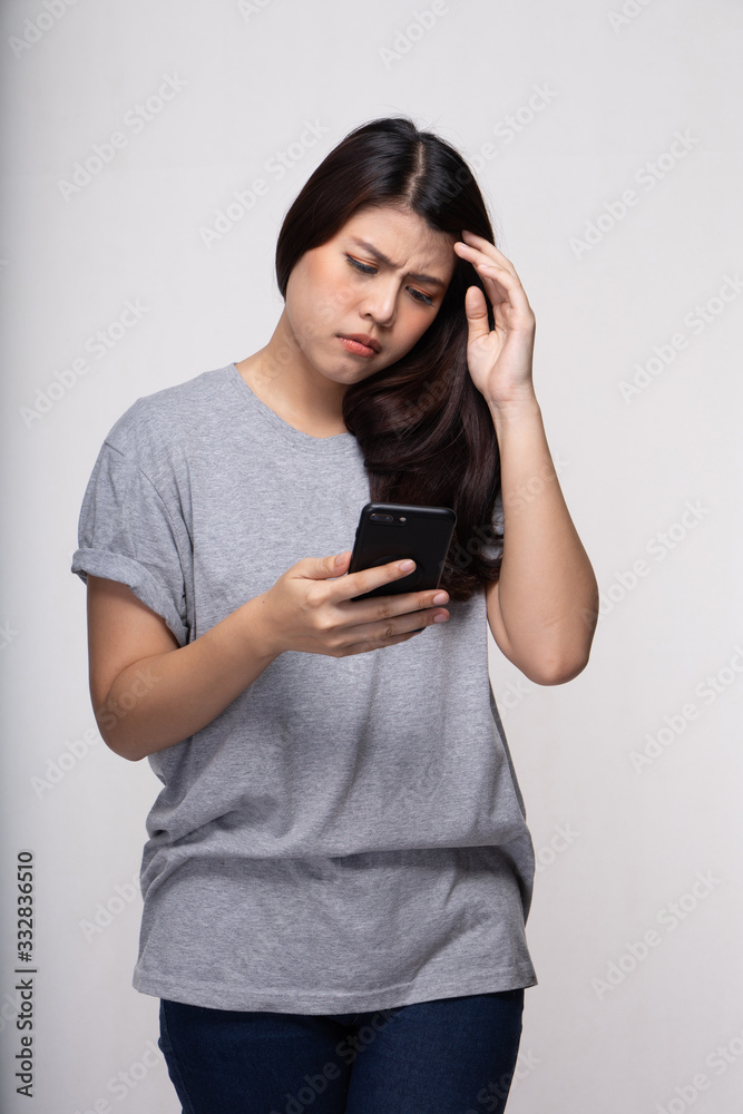 Young stressed woman using mobile phone text sms. Asian girl holding cellphone typing text message with serious face. Young stressed woman using mobile phone text sms. Asian girl holding cellphone typing text message with serious face.