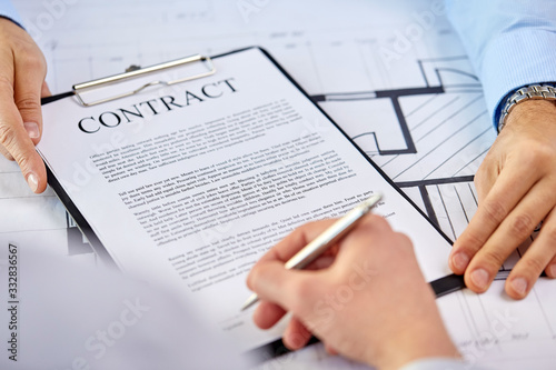 real estate business, sale and people concept - male realtor's hands and customers signing property purchase contract at office