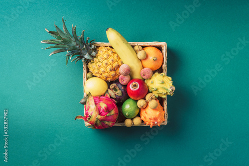 Fototapeta Naklejka Na Ścianę i Meble -  Tropical fruits on green background. Rattan box full of exotic thailand fruits - pineapple, pitahaya, kiwano, african horned melon, tamarillo fruit, granadilla, feijoa, salak, snake fruits, maracuya