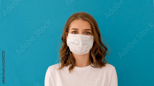 Woman putting on surgical mask for corona virus prevention on blue background photo
