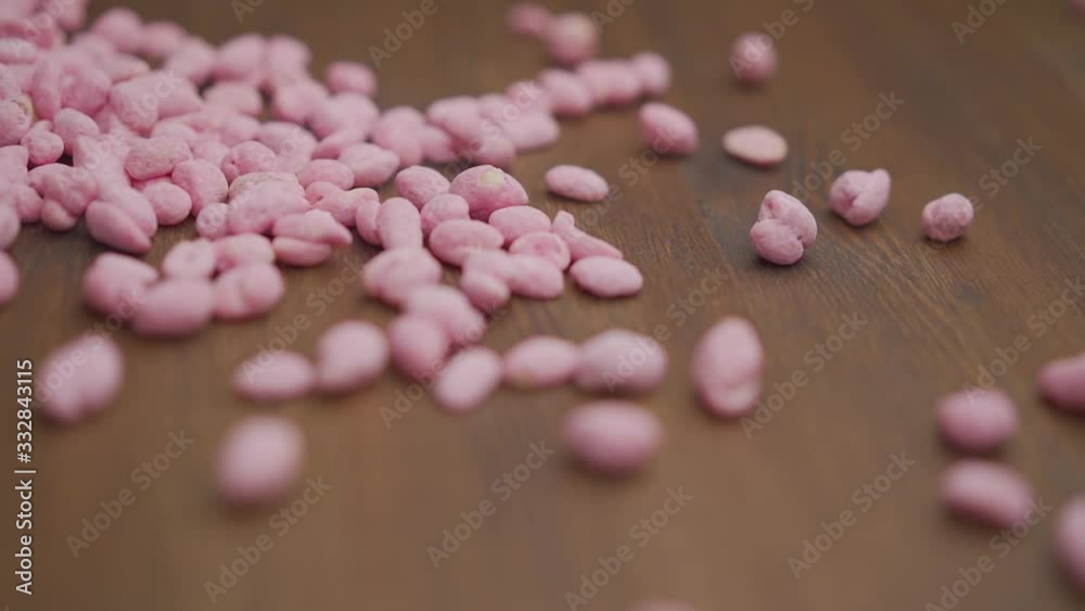 Peanuts in cranberries. Pink nuts in slow motion spilled onto the table. Flat lay or top view pink peanuts on a wooden table. Pink peanuts spilled on the table. Peanuts in cranberries. Pink nuts in slow motion spilled onto the table. Flat lay or top view pink peanuts on a wooden table. Pink peanuts spilled on the table.