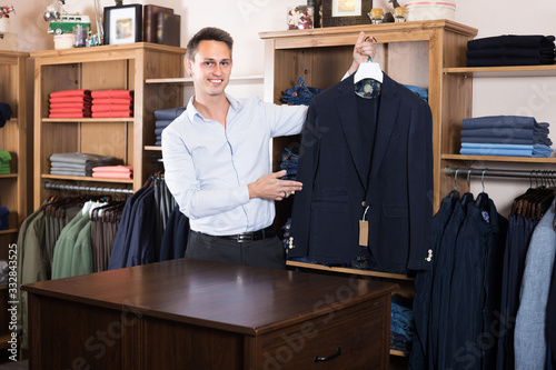Smiling guy is deciding on for new dark blue suit