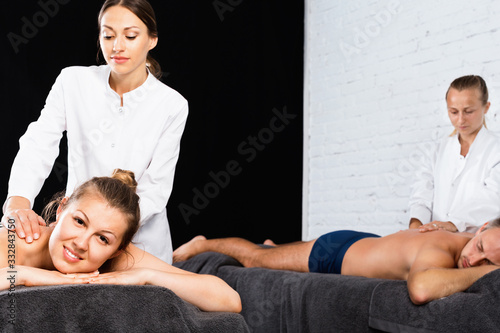 Woman and man enjoying relaxing massage by professional masseuses photo