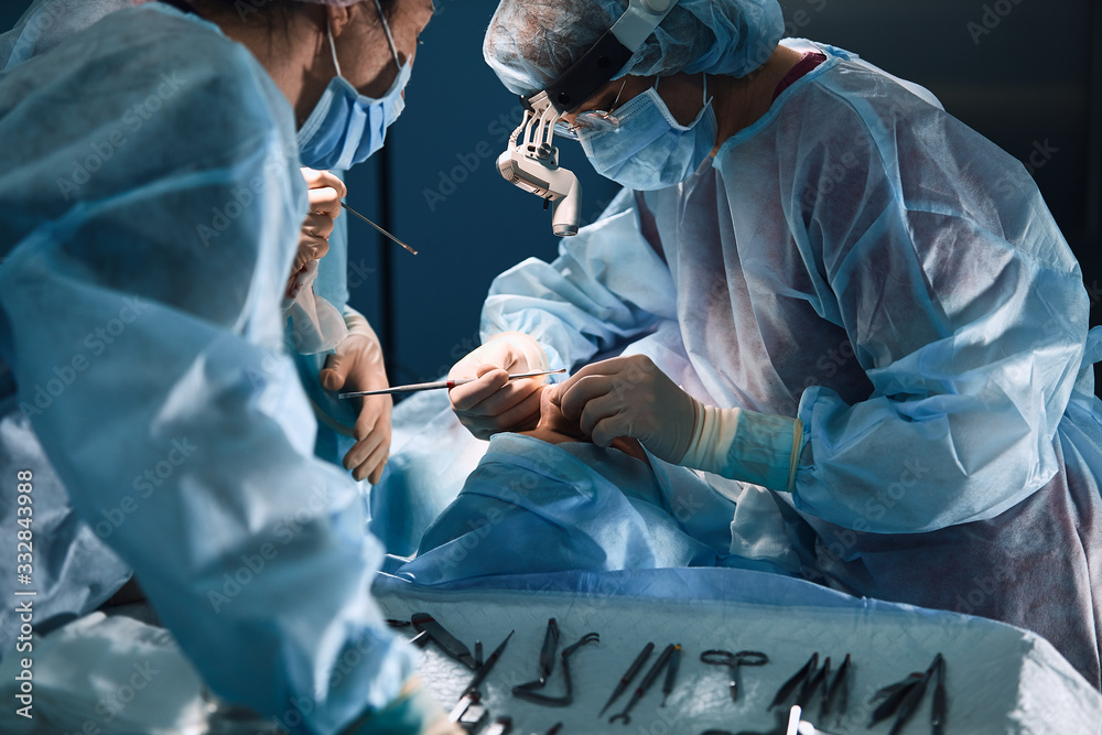 In the hospital operating room. An international team of professional surgeons and assistants works in a modern operating room. Professional doctors celebrate successfully saved lives. - obrazy, fototapety, plakaty 