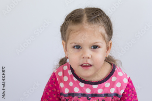 Portrait of caucasian child of three years old looking at camera with shiny eyes on the white background