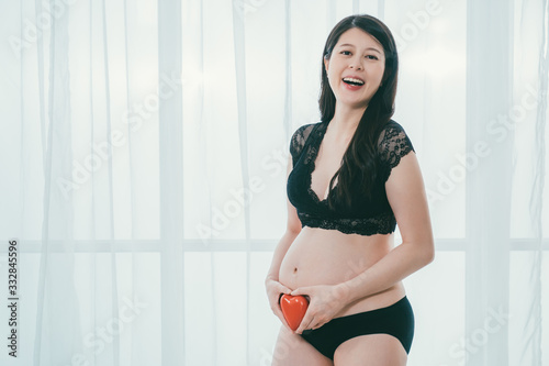 Pregnancy maternity. cheerful asian pregnant mother holding red heart shape at bare belly and laughing joyful. fashion future mom in black lace bra and panties show love to unborn twins baby Free Download Pregnancy maternity. cheerful asian pregnant mother holding red heart shape at bare belly and laughing joyful. fashion future mom in black lace bra and panties show love to unborn twins baby - GFXLoad