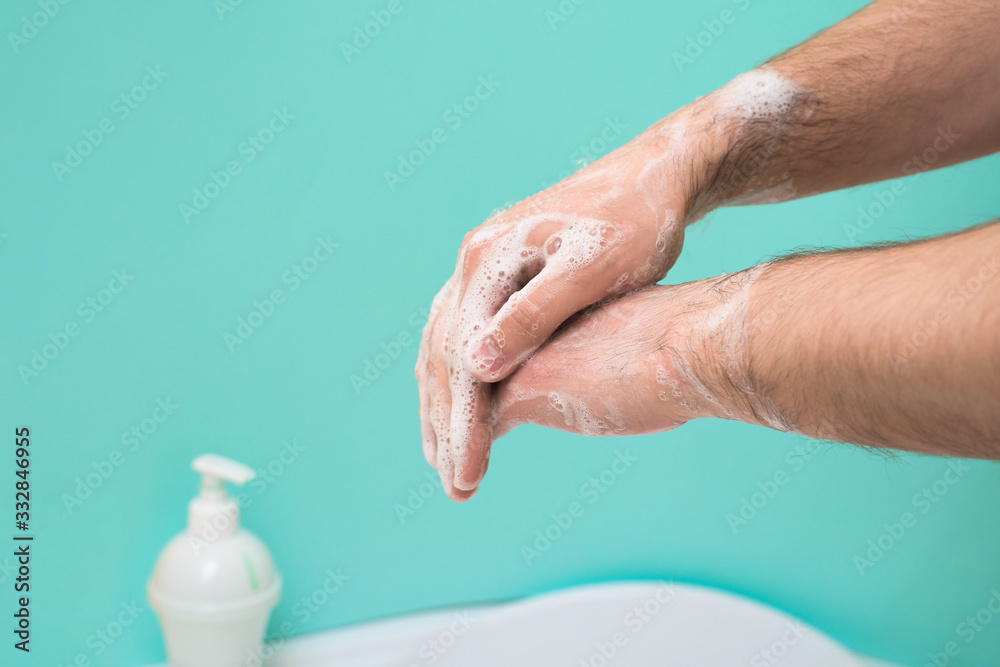 Fototapeta premium wash your hands with disinfectant soap during a coronavirus infection. close-up of a hand in soap foam. antibacterial treatment of the hands. on a blue background