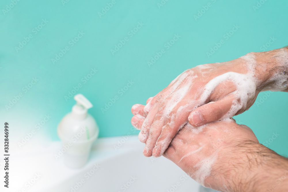 Fototapeta premium wash your hands with disinfectant soap during a coronavirus infection. close-up of a hand in soap foam. antibacterial treatment of the hands. on a blue background