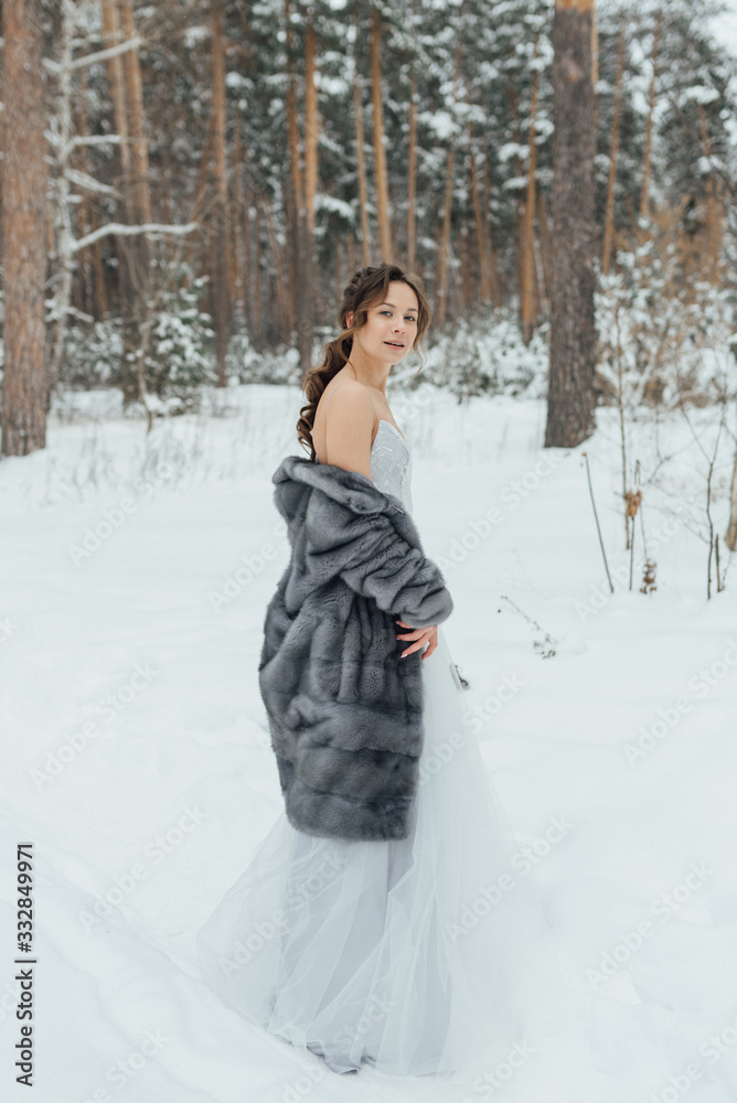 a beautiful girl in a wedding dress stands in a winter pine forest a beautiful girl in a wedding dress stands in a winter pine forest