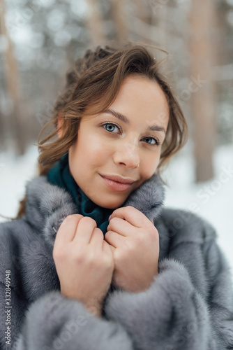 a beautiful girl in a wedding dress stands in a winter pine forest