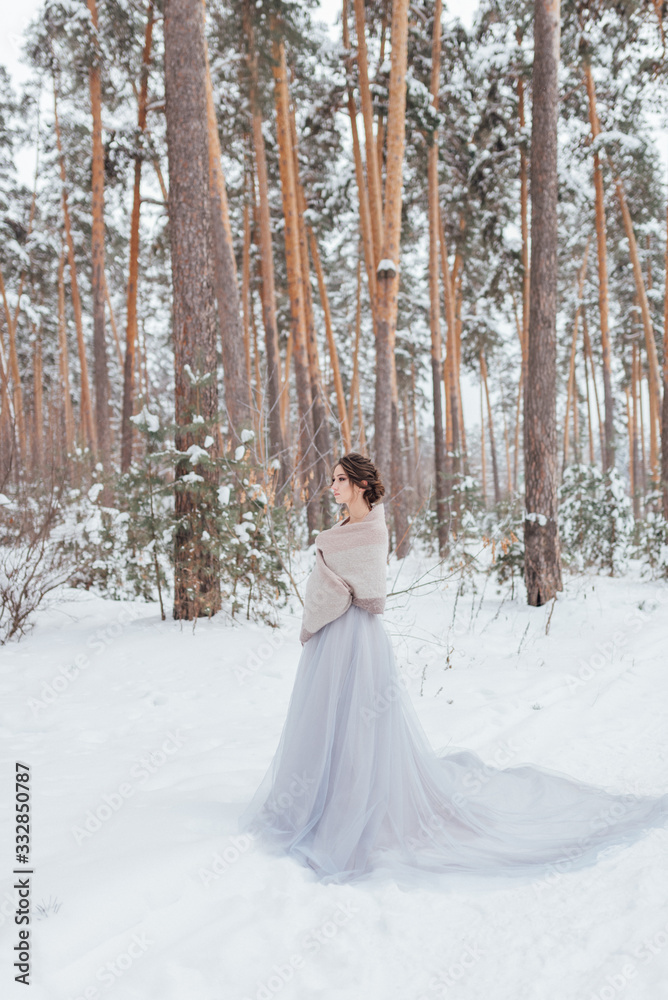 a beautiful girl in a wedding dress stands in a winter pine forest a beautiful girl in a wedding dress stands in a winter pine forest