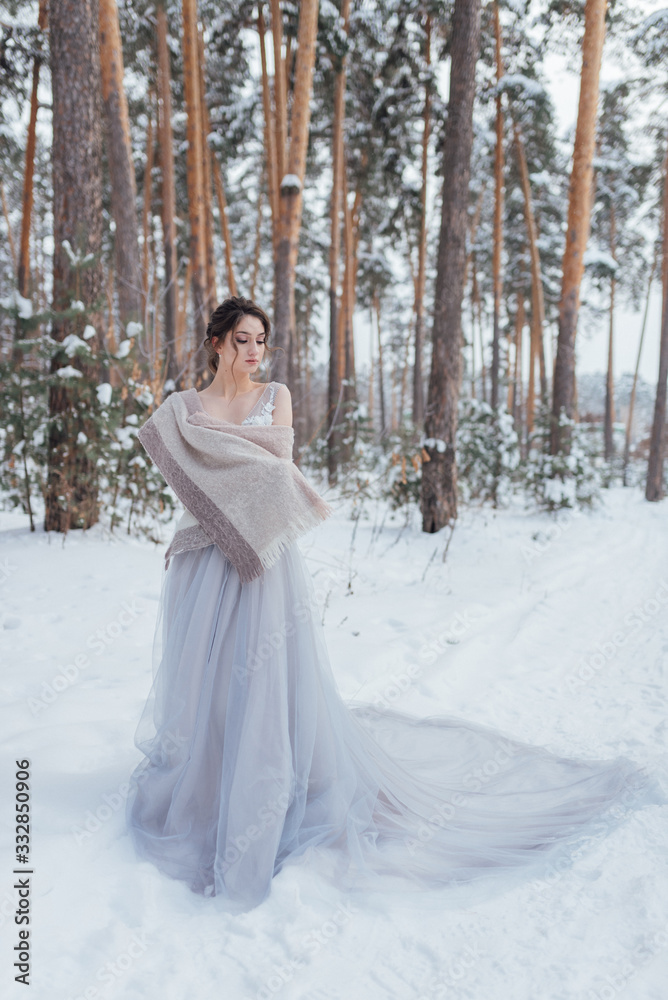 a beautiful girl in a wedding dress stands in a winter pine forest a beautiful girl in a wedding dress stands in a winter pine forest