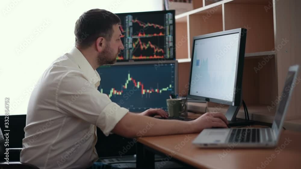 Stockbroker in white shirt is working in a monitoring room with display screens. Stock Exchange Trading Forex Finance Graphic Concept. Businessmen trading stocks online. Stockbroker in white shirt is working in a monitoring room with display screens. Stock Exchange Trading Forex Finance Graphic Concept. Businessmen trading stocks online.