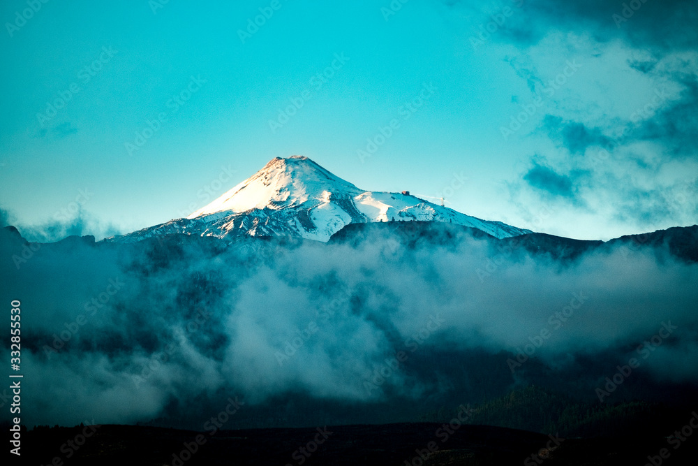 Beautiful snowy top of vulcan mountains with blue sky and clouds around