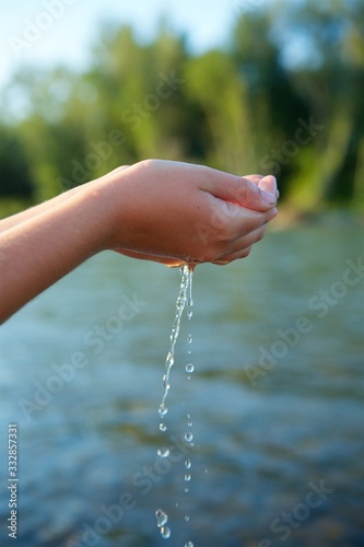 A girl's hand or a girl's hand holds clean river or sea water in the wild.