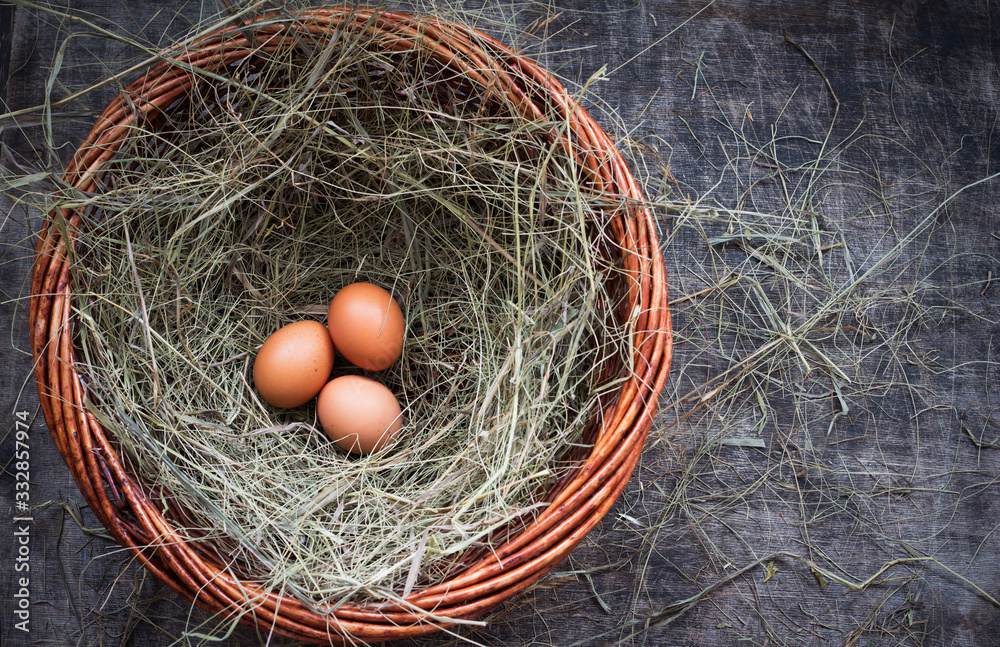 Three chicken eggs in a straw nest for Easter, rustic style, table, top view, copy space right