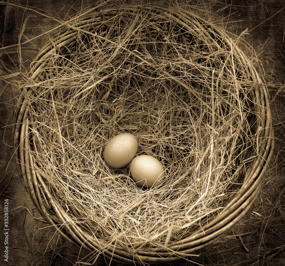 Two chicken eggs in a basket with straw for Easter, rustic style, table, top view, toned antique, left side Two chicken eggs in a basket with straw for Easter, rustic style, table, top view, toned antique, left side