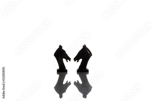 Silhouette of two vintage horses chess isolated on white background with reflection on the floor