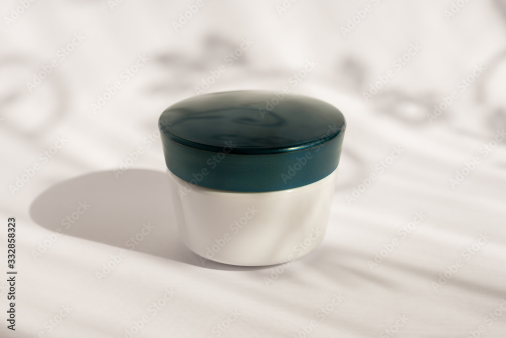 White blank mockup of bottle cream container with blue cup. Monstera shadows. Professional tubes for facial and body treatment. White blank mockup of bottle cream container with blue cup. Monstera shadows. Professional tubes for facial and body treatment.