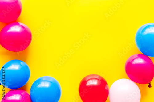 Colorful balloons frame on yellow background top-down frame copy space