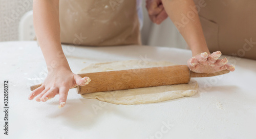 Granny's baking class. Unrecognizable child rolling dough with grandmother at table, closeup © Prostock-studio