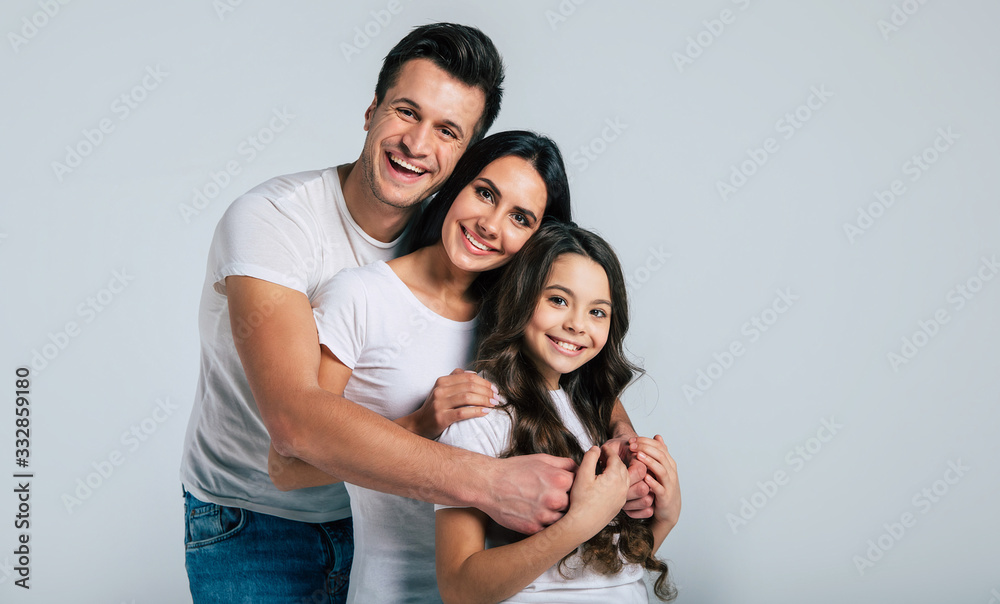 Beautiful excited and the funny family team is posing and pointing in a white t-shirt while they isolated on white background in studio. Beautiful excited and the funny family team is posing and pointing in a white t-shirt while they isolated on white background in studio.