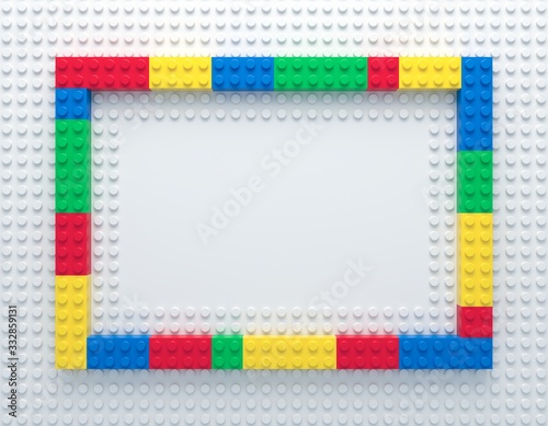 Frame of colorful toy bricks on white construction plate with place for your ...
