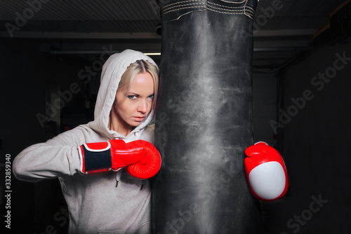A young girl in Boxing gloves and a stern look poses with a pear in the gym.