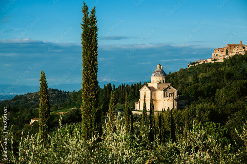 Santuario di San Biagio. Tuscany, rural landscape. Countryside farm, cypresses trees, green field, sun light and cloud. Italy, Europe.