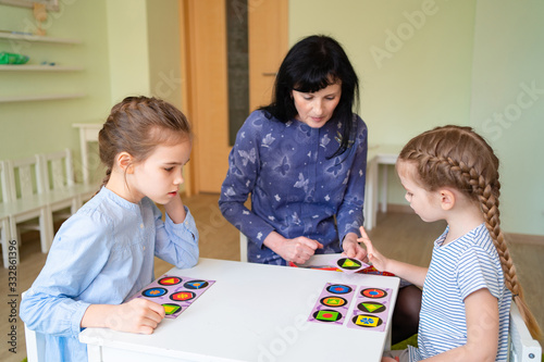 teacher with children play cards geometric shapes