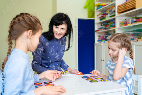 teacher with children play cards geometric shapes.