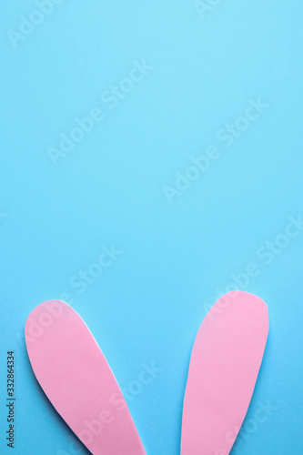 Top view of paper bunny ears on blue background, space for text. Easter celebration