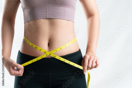 young woman measuring her belly waist with measure tape, woman diet lifestyle concept