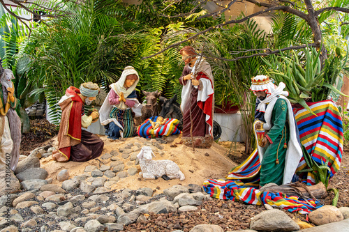 Christmas nativity scene surrounded by green palm leaves with ceramic figurines