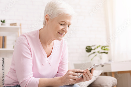 Senior woman chatting on smartphone with family at home