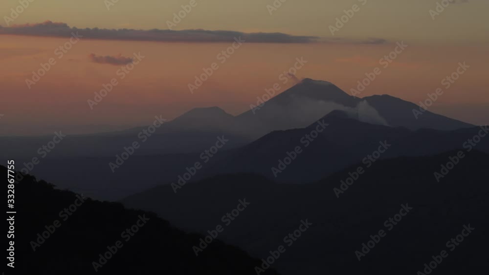 Zoom in timelapse of Telica and San Cristóbal volcano, in Nicaragua, smoking in the distance behind layers of hills and mountains during sunset. Zoom in timelapse of Telica and San Cristóbal volcano, in Nicaragua, smoking in the distance behind layers of hills and mountains during sunset.