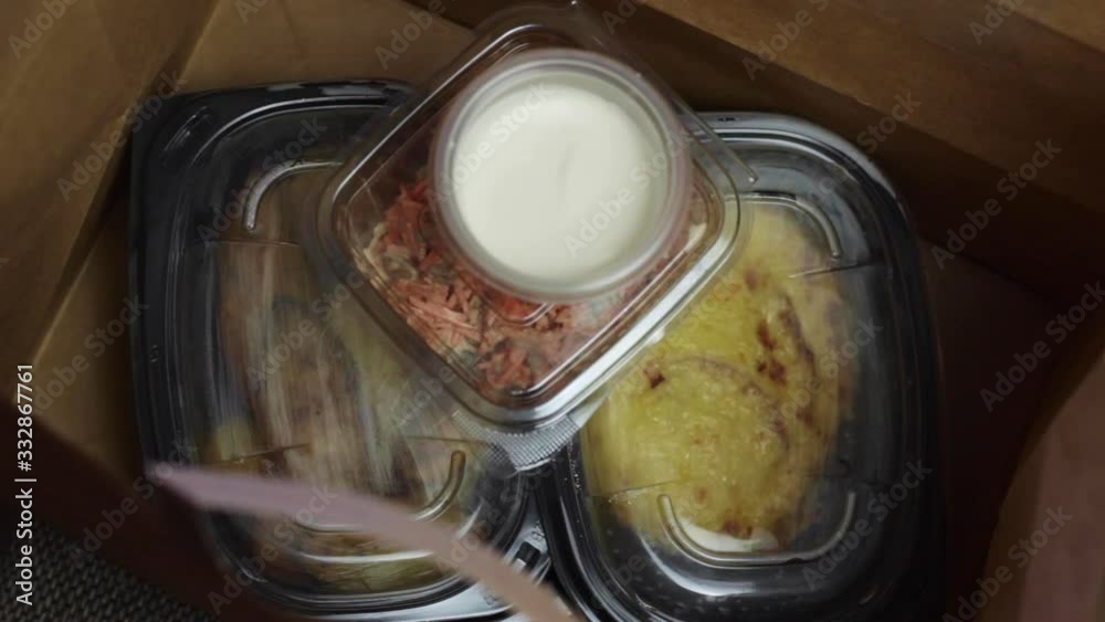Take-away food in a paper bag with plastic containers and potatoes