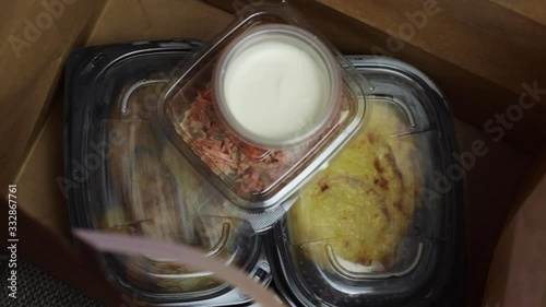 Take-away food in a paper bag with plastic containers and potatoes