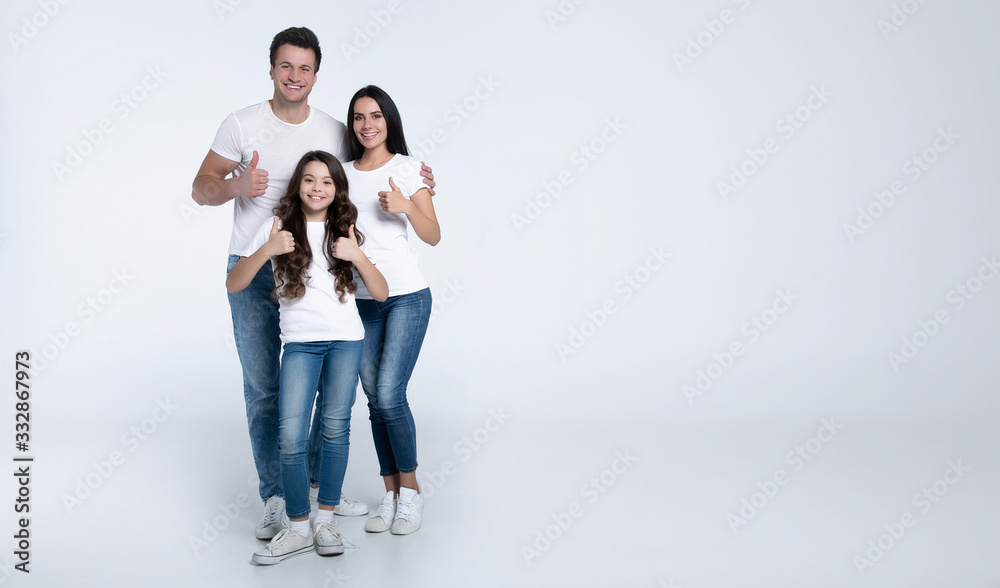 Beautiful excited and the funny family team is posing and pointing in a white t-shirt while they isolated on white background in studio. Beautiful excited and the funny family team is posing and pointing in a white t-shirt while they isolated on white background in studio.