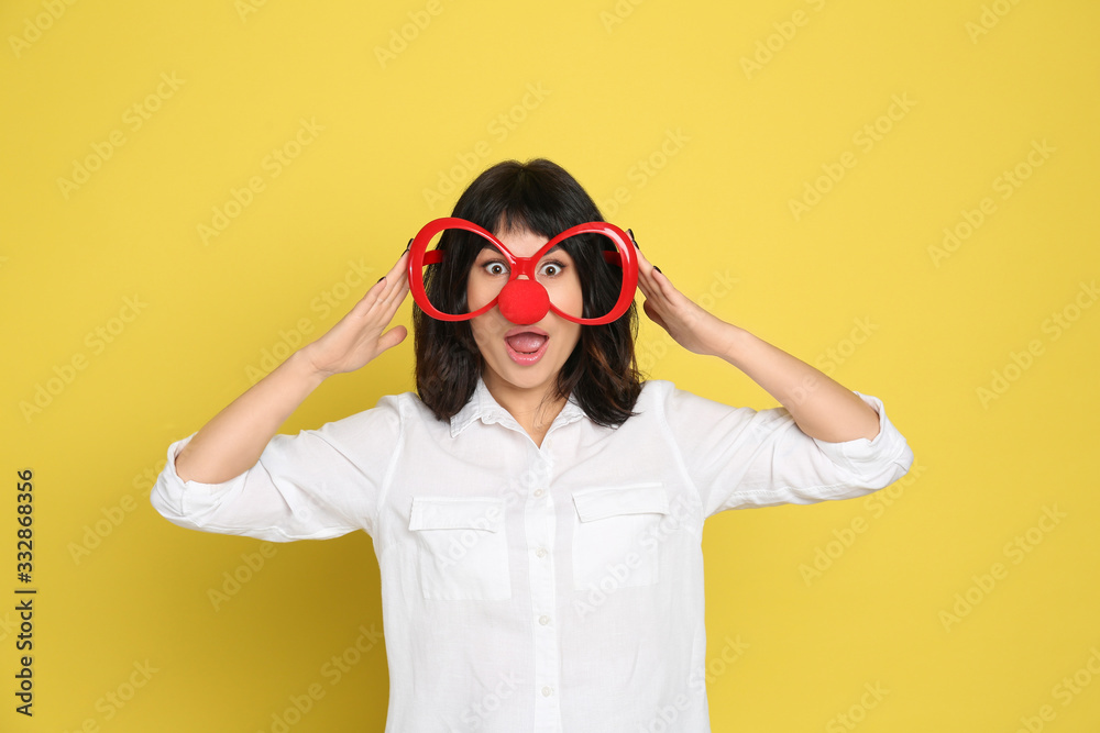 Funny woman with clown nose and large glasses on yellow background. April fool's day