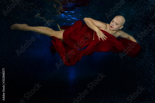 Girl without hair is happy, underwater photo, remission of a bald girl
