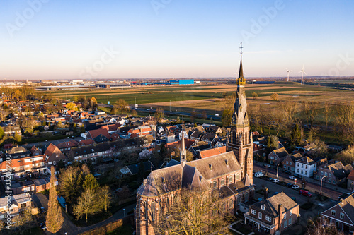 A church and windmills during sunrise on a sunny morning in the dutch town of Waalwijk, Noord Brabant, Netherlands
