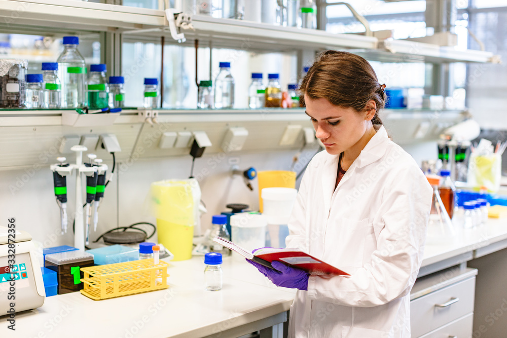 Girl scientist studying notes near lab equipment Girl scientist studying notes near lab equipment